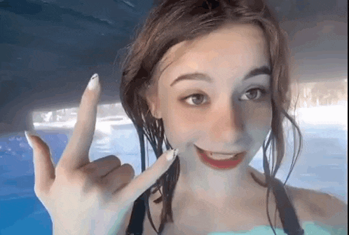 a woman in a bikini is making a peace sign in a pool .