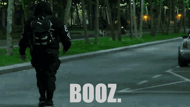 a man with a backpack walks down a street with the word booz on the bottom