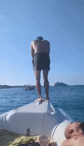 a man standing on the back of a boat in the water