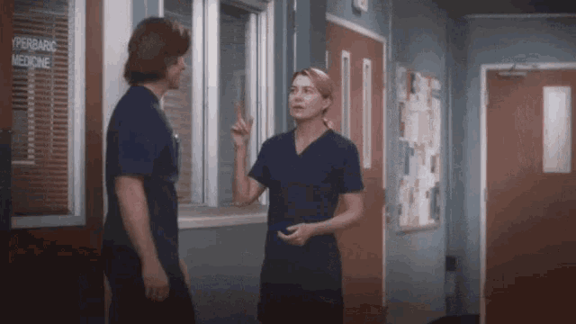 a man and a woman are standing next to each other in a hallway talking .