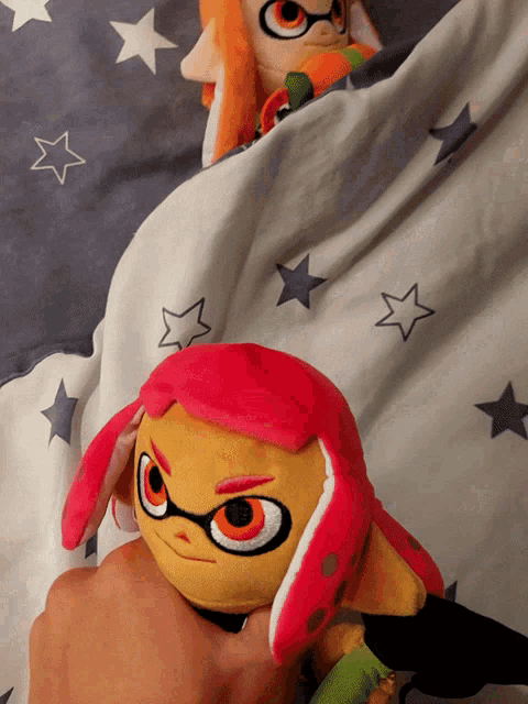two stuffed animals are laying on a blanket with stars