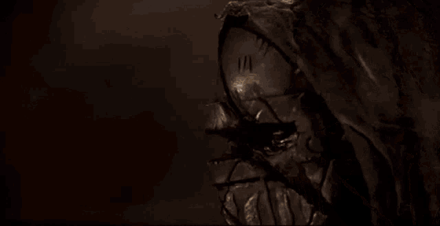 a close up of a person wearing a mask in a dark room with a dark background .
