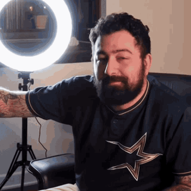 a man with a beard is wearing a blue shirt with a gold star on it
