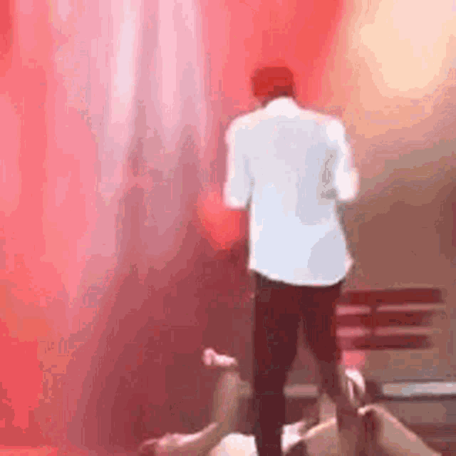 a man in a white shirt is standing on a stage next to a man laying on the floor .