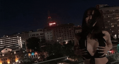 a woman is standing in front of a city skyline with a building that says angels lofts on it