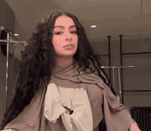 a woman with long curly hair and a scarf around her neck