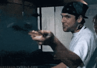 a man wearing a bandana and a white shirt is pointing at something