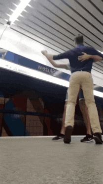 two men are dancing in front of a sign that says " wesu "