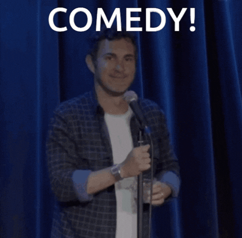 a man standing in front of a microphone with the word comedy written above him