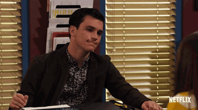 a man sits at a desk in front of a window with a netflix logo on the bottom