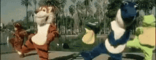 a group of mascots are dancing together in a park .