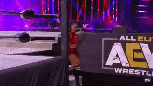 a female wrestler is standing in front of a sign that says all elite wrestling .