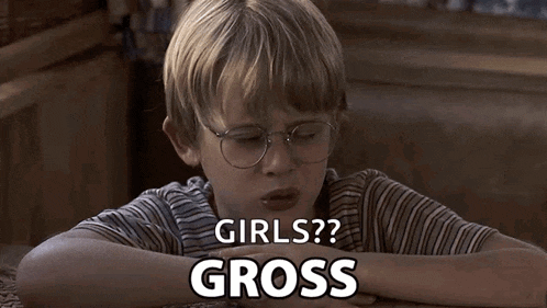 a little boy with glasses is sitting at a table and says girls gross