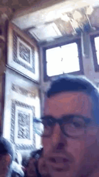 a man wearing glasses is taking a selfie in a room