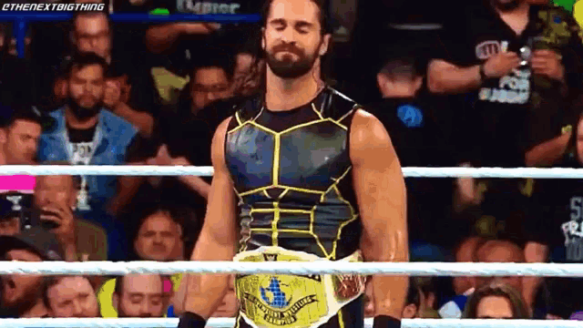 a wrestler is standing in a ring with his eyes closed and a belt around his waist .
