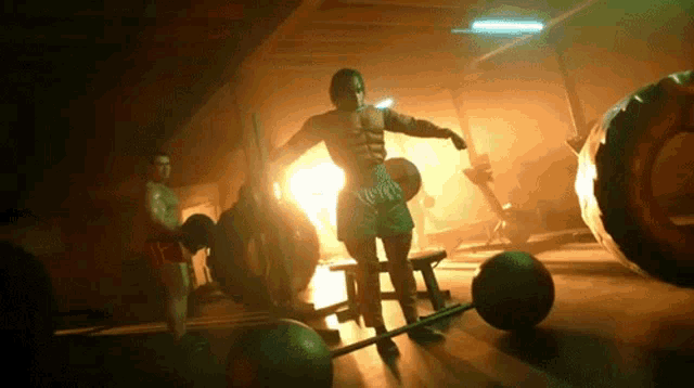 a man stands on a bar in a gym surrounded by balls