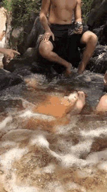 a group of people are sitting on rocks in a stream .