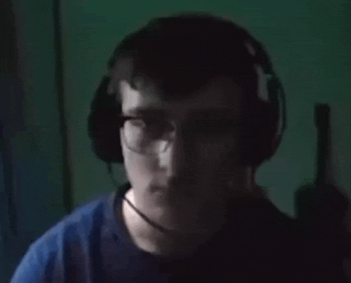 a young man wearing glasses and headphones is looking at the camera .