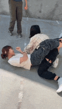 a woman is laying on the ground with her legs crossed while another woman stands behind her