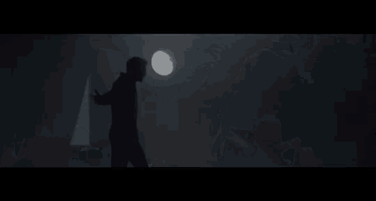 a man with antlers is standing in the middle of a forest .
