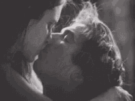 a black and white photo of a man and woman kissing each other .