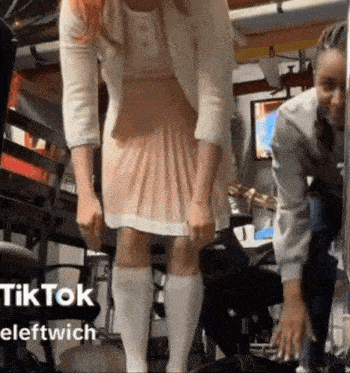 a woman in a pink dress and white knee high socks stands next to a man in a suit .