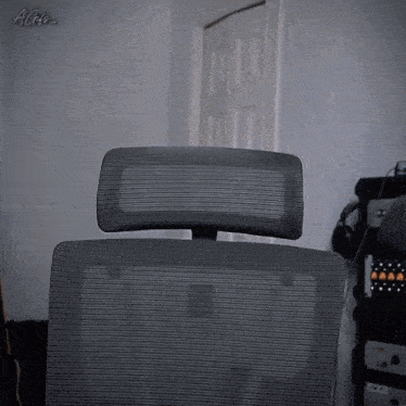 a gray chair with a mesh back and headrest is in a room with a sign that says agz