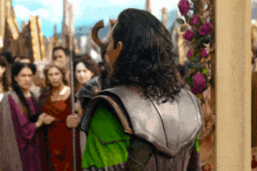 a man with long hair and a green shirt stands in front of a crowd