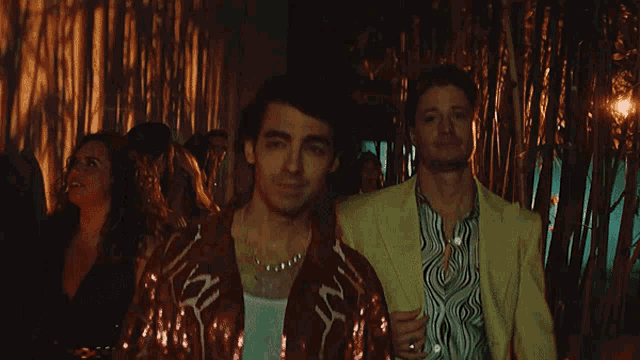 a man in a red jacket with the word love on it is standing next to another man in a yellow jacket