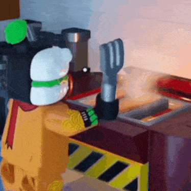 a lego character is standing in front of a stove holding a spatula and fork .
