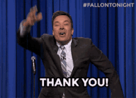 a man in a suit and tie says thank you in front of a blue curtain