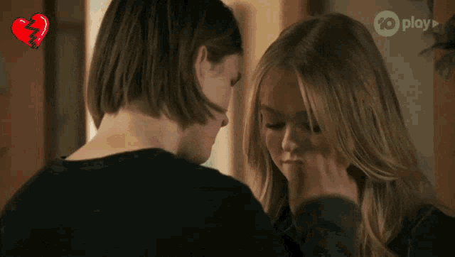 a couple of girls looking at each other with a broken heart behind them that says play