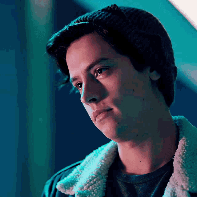 a close up of a young man wearing a beanie and a sherpa jacket