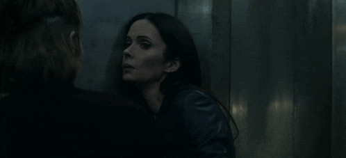 a woman is leaning against a wall and talking to another woman in a dark room .