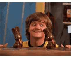 a man behind a counter with two chocolate bunny figurines on it