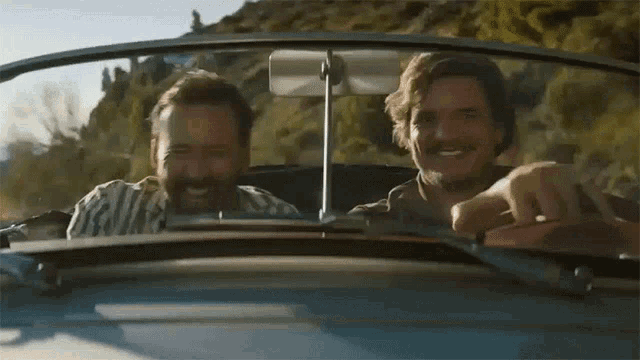 two men are laughing while driving a car on a road