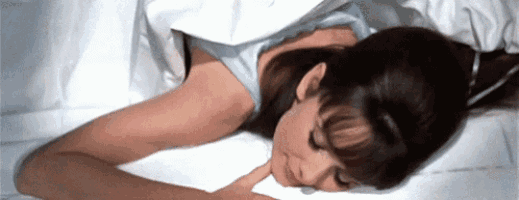 a woman is laying on a bed with her hand on her face .