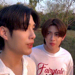 two young men are standing next to each other in a field .