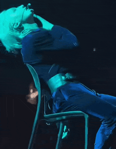 a person in a blue outfit is sitting in a chair on a stage