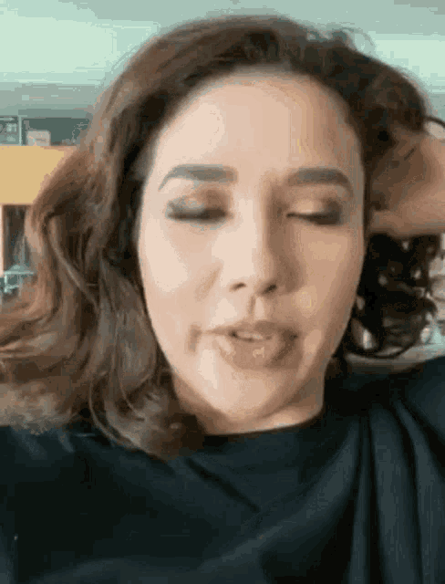 a close up of a woman with her eyes closed holding her hair .