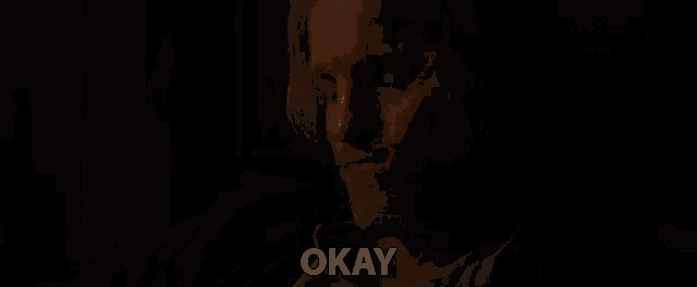 a man in a dark room with the word okay written on the bottom