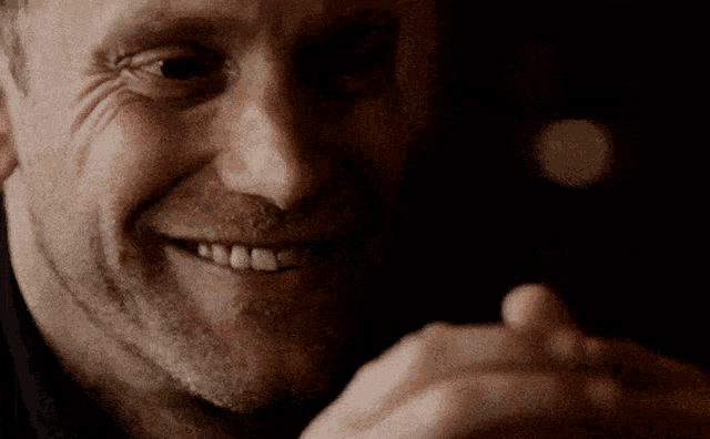 a close up of a man 's face smiling and pointing