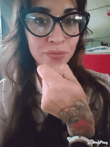 a woman wearing glasses and a tattoo on her arm has a watch on her wrist