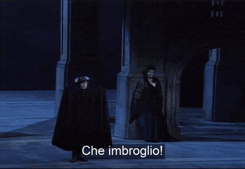 a man in a black cape stands next to a woman in a black dress and the words che imbroglio are on the screen