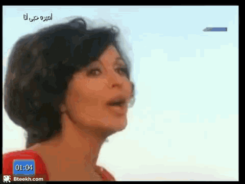a woman in a red dress is singing in front of a blue screen that says 1:04