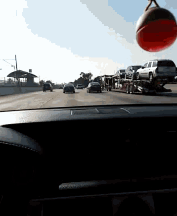 a car driving down a highway with a basketball hanging from the rear view mirror