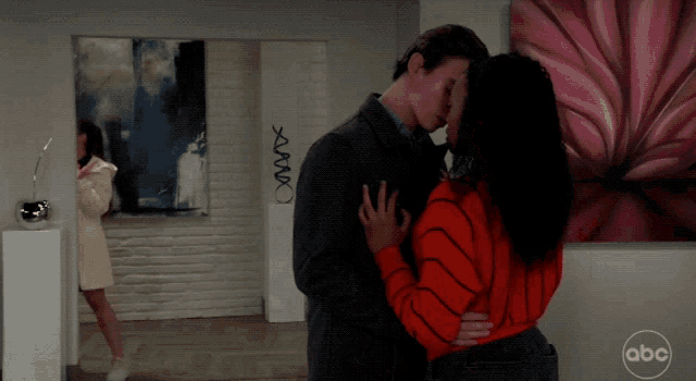 a man and woman are kissing in a room with a abc logo