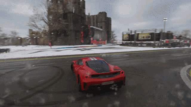 a red sports car is driving down a snow covered road