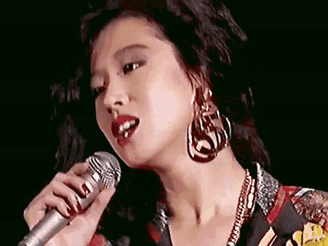 a woman singing into a microphone with red lipstick