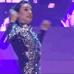 a woman singing into a microphone on a stage in front of a large screen